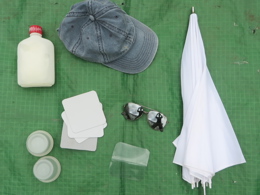 Layed out equipment in my day kit, including umbrella, sun cap and glasses, small pots and lids and frozen water bottle